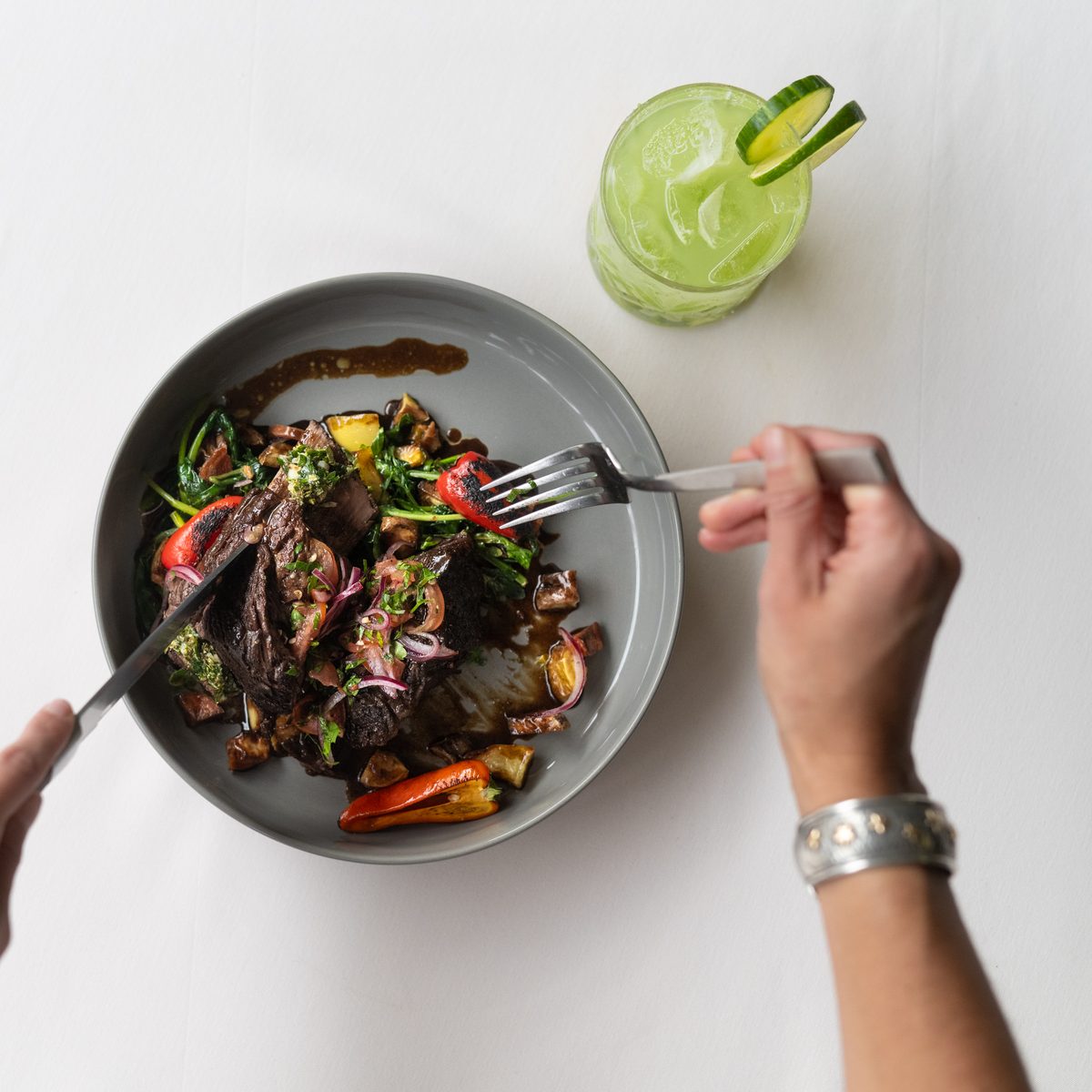 Guest tasting a plate of grilled steak with charred peppers during a Provisions menu tasting