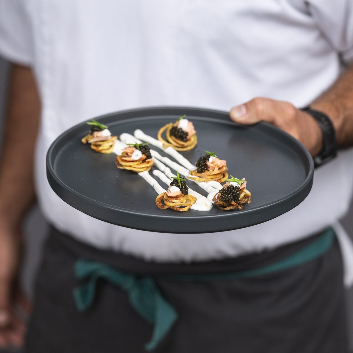 Provisions chef holding a plate of appetizers topped with caviar