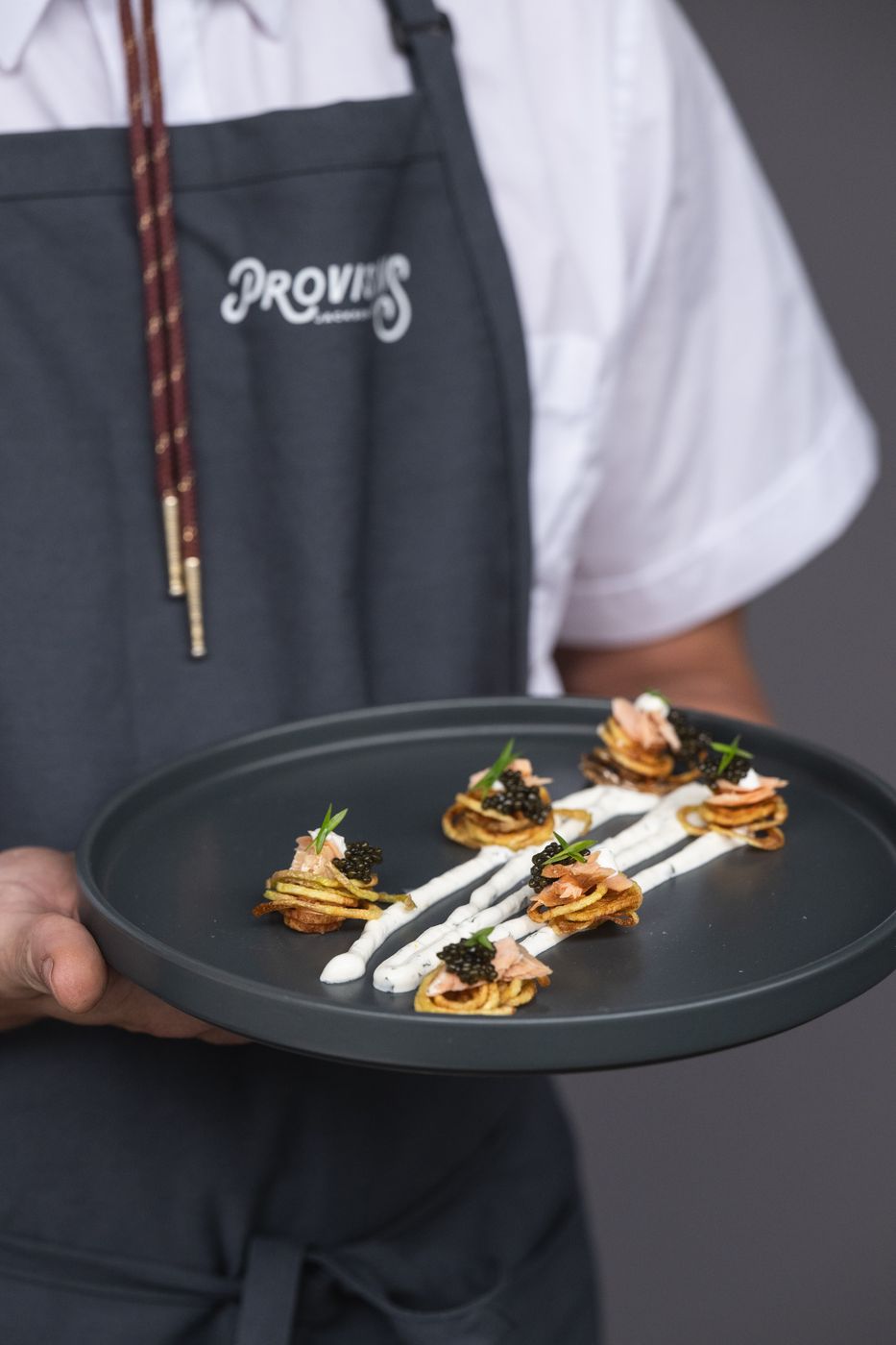 Server holding a plate of blini appetizers with crème fraîche