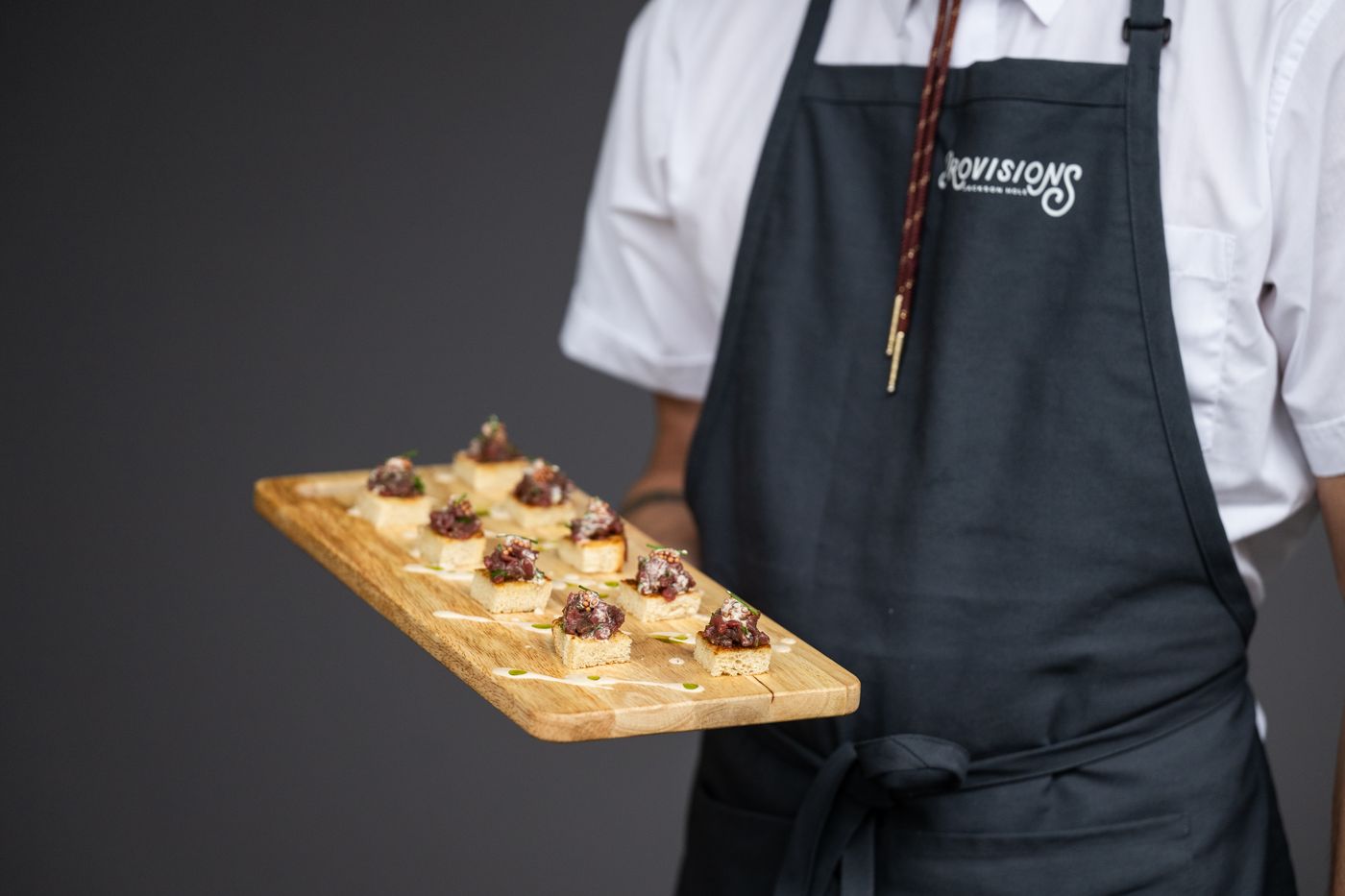Server holding a wooden board of passed appetizers