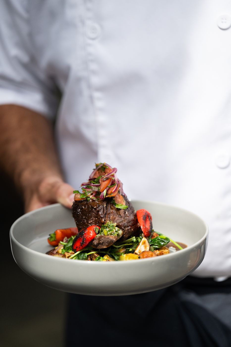 Chef holding a bowl of braised short rib with charred peppers