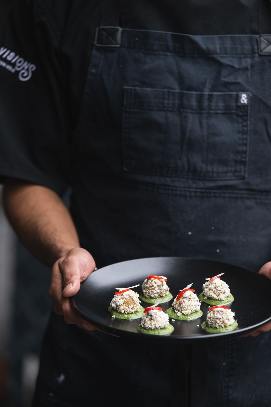 Server holding a plate of cucumber and crab bites