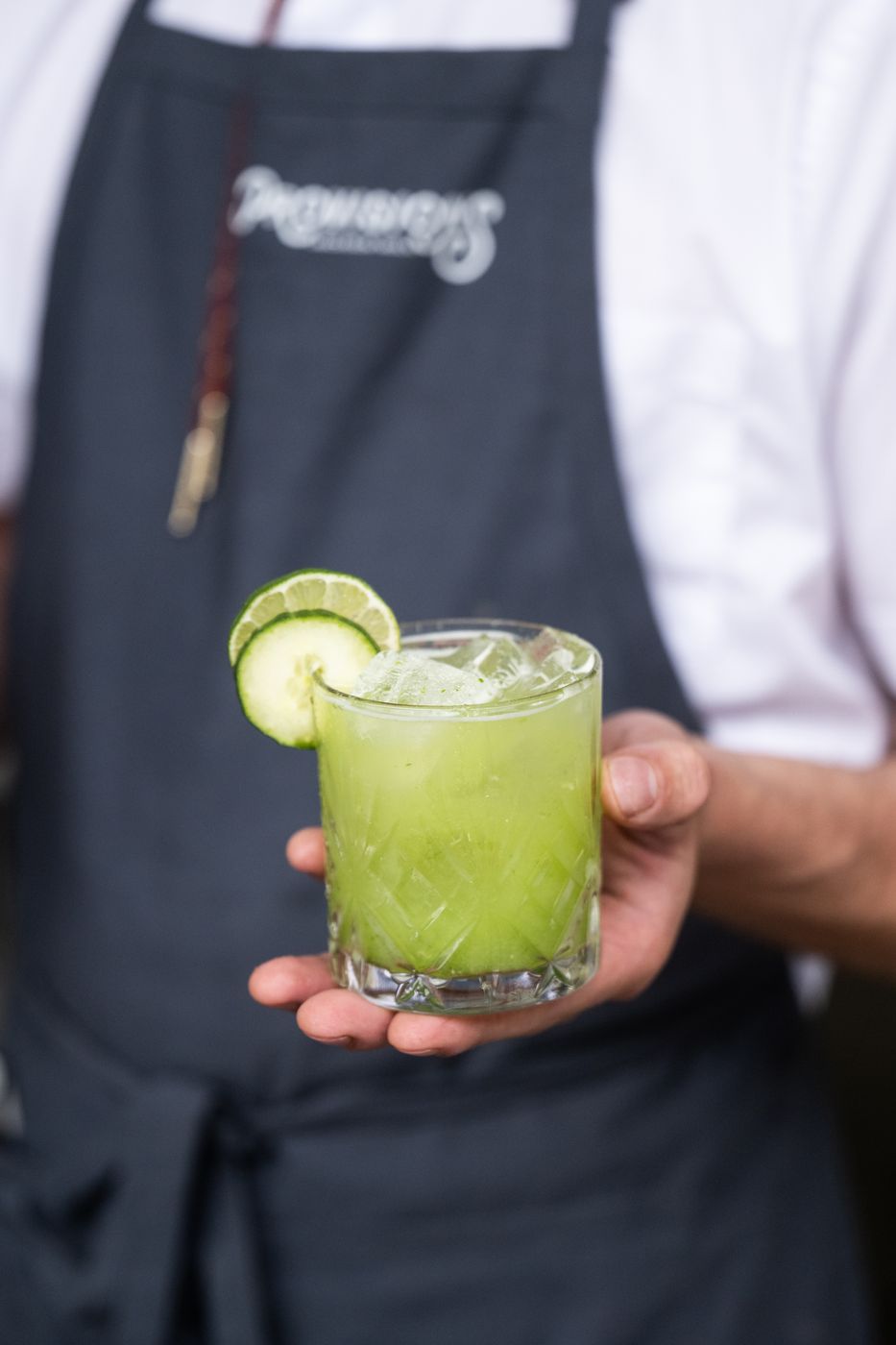 Server holding a cucumber lime cocktail