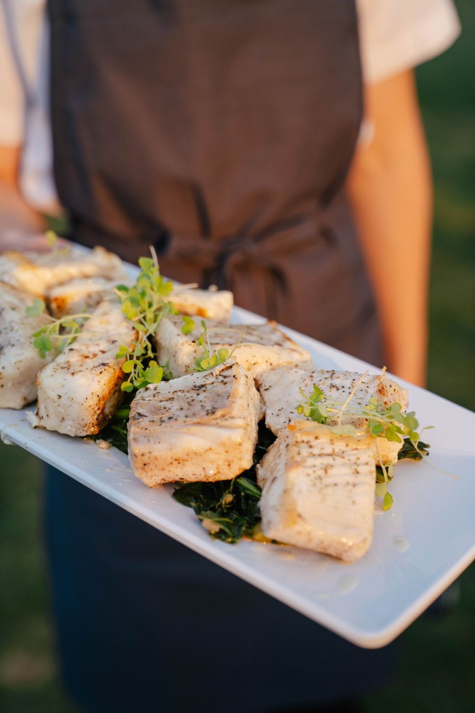 Family style platter of fish with greens