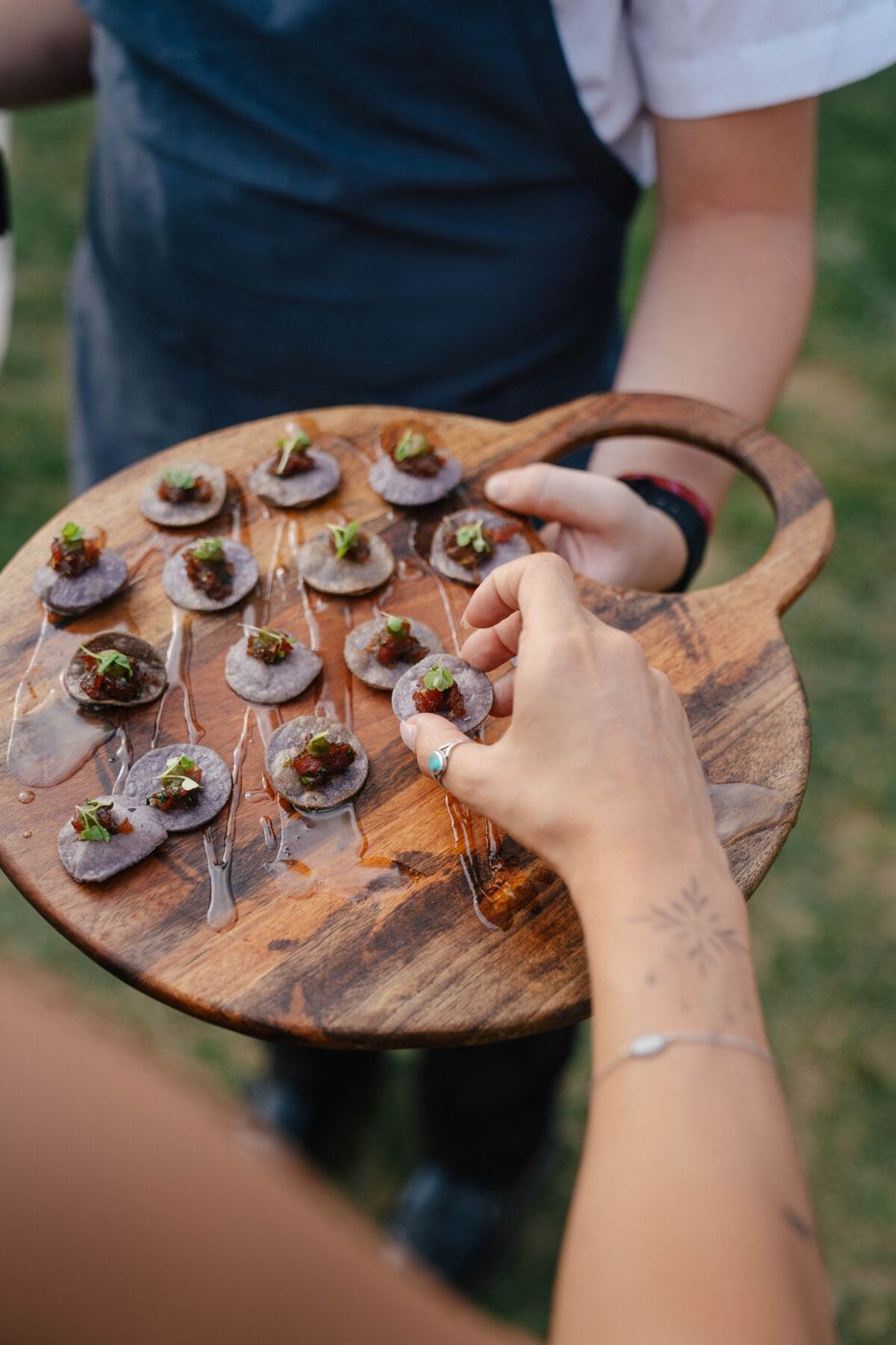 Guests reaching for bites on a wooden serving board
