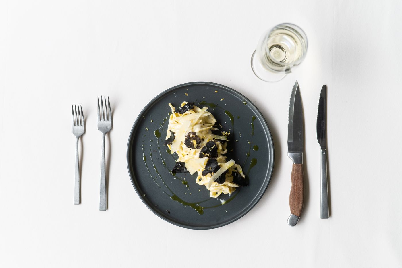 Plated pasta at a place setting on a white table