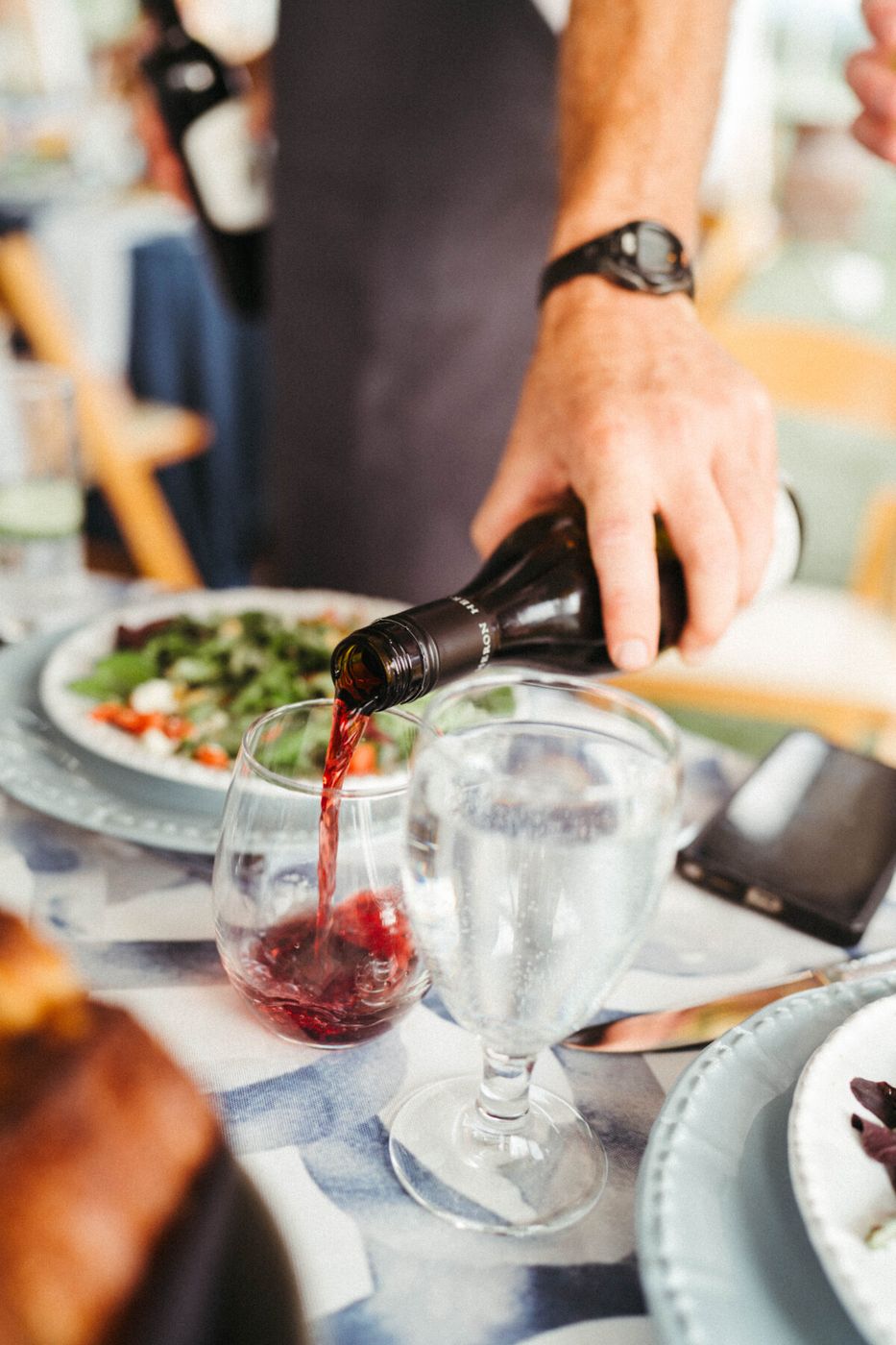 Server pouring red wine at a dinner table