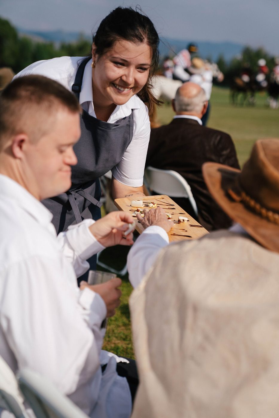 Provisions server offering appetizers to seated guests outdoors