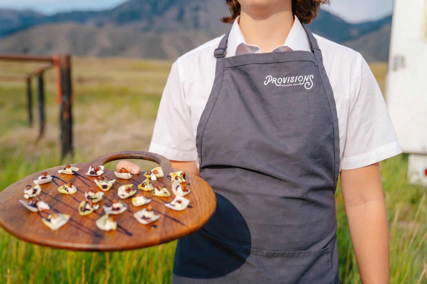 Server holding a board of appetizers in a Jackson Hole meadow