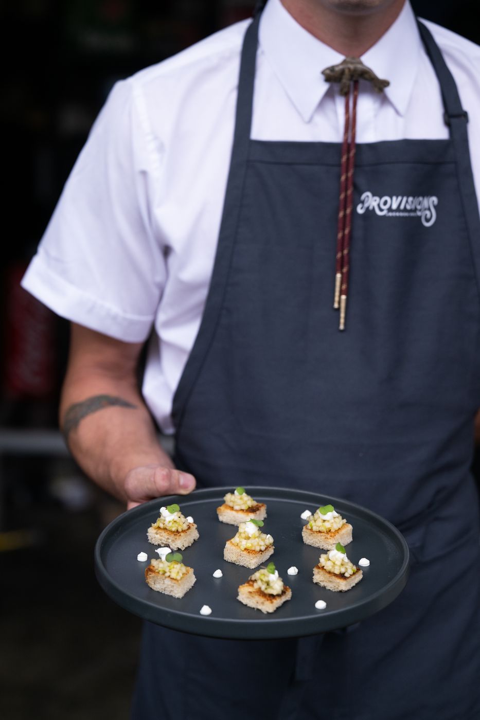 Provisions server holding a plate of passed canapés