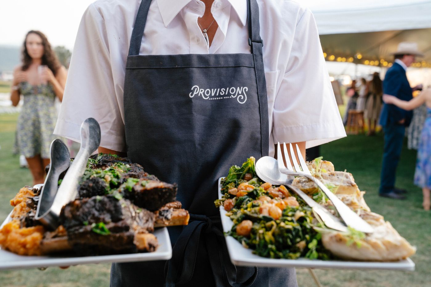 Server carrying two platters at a wedding reception