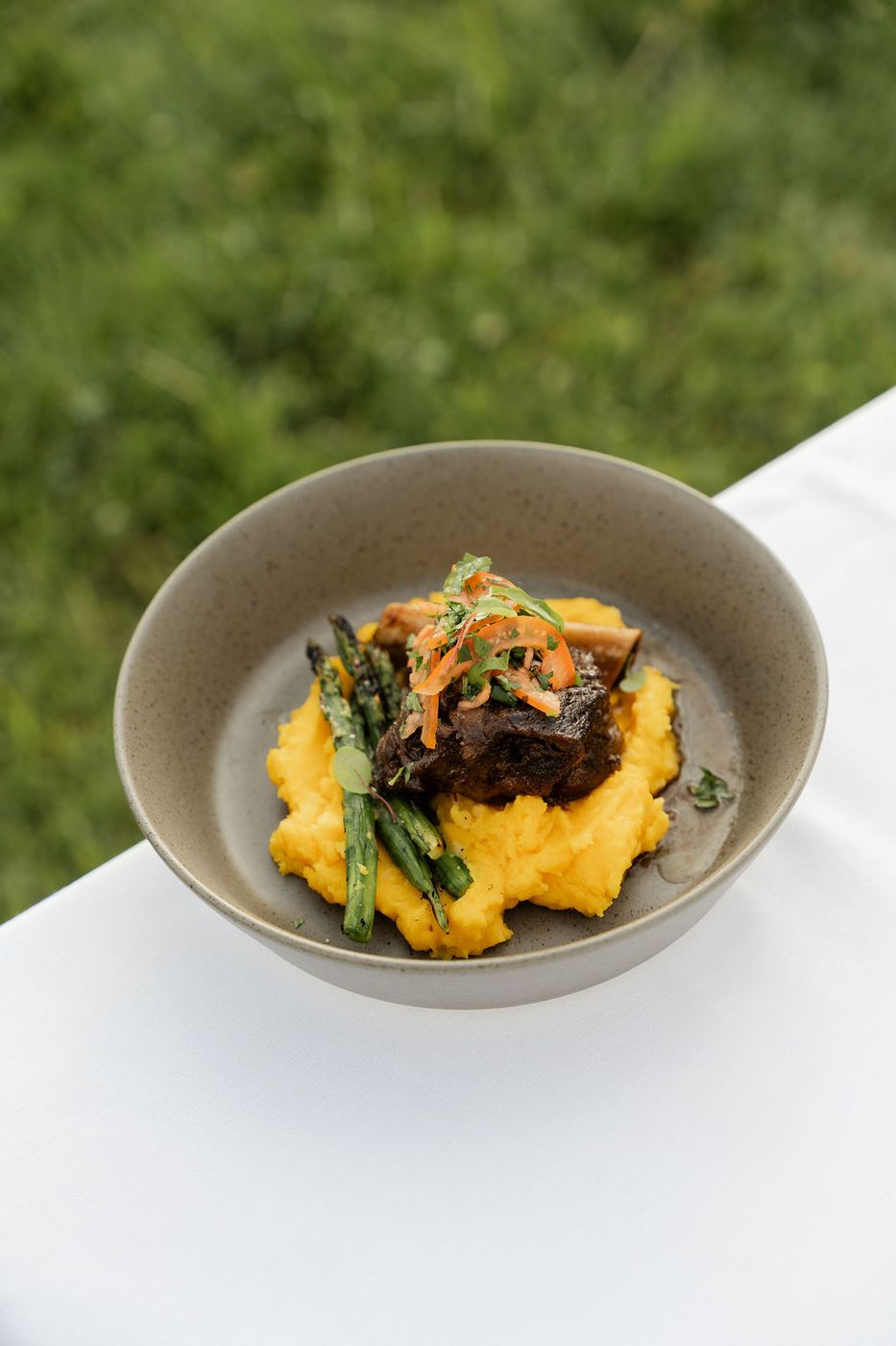 Short rib over polenta in a stoneware bowl