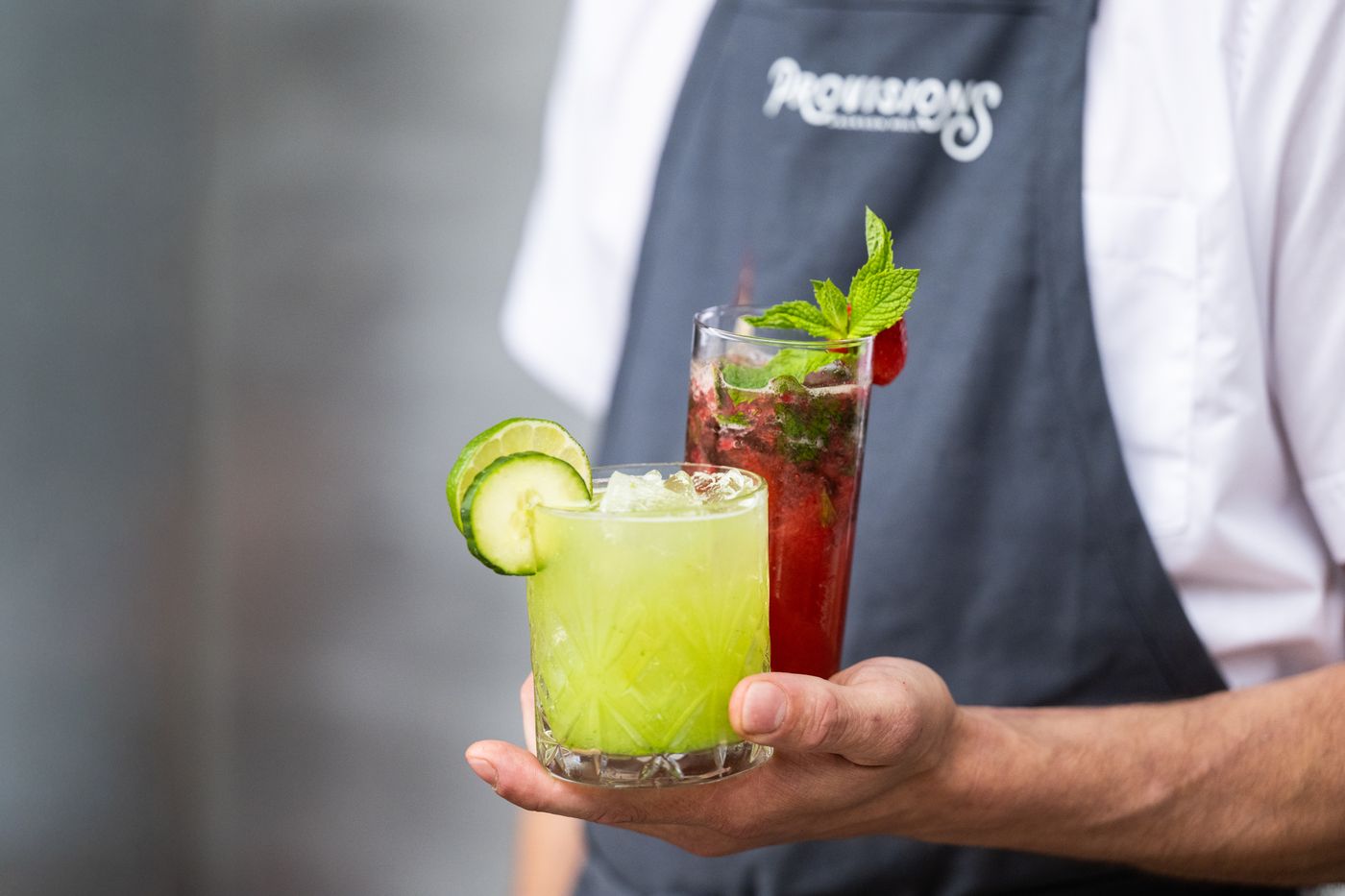 Two signature cocktails held by a Provisions bartender