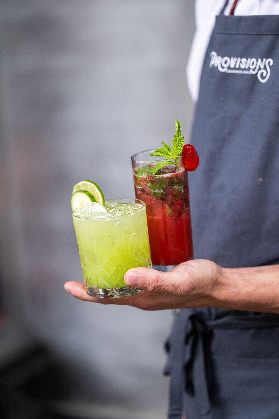 Server holding two signature cocktails