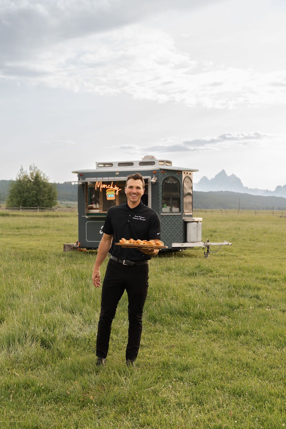 Chef holding a tray in a field by the food truck