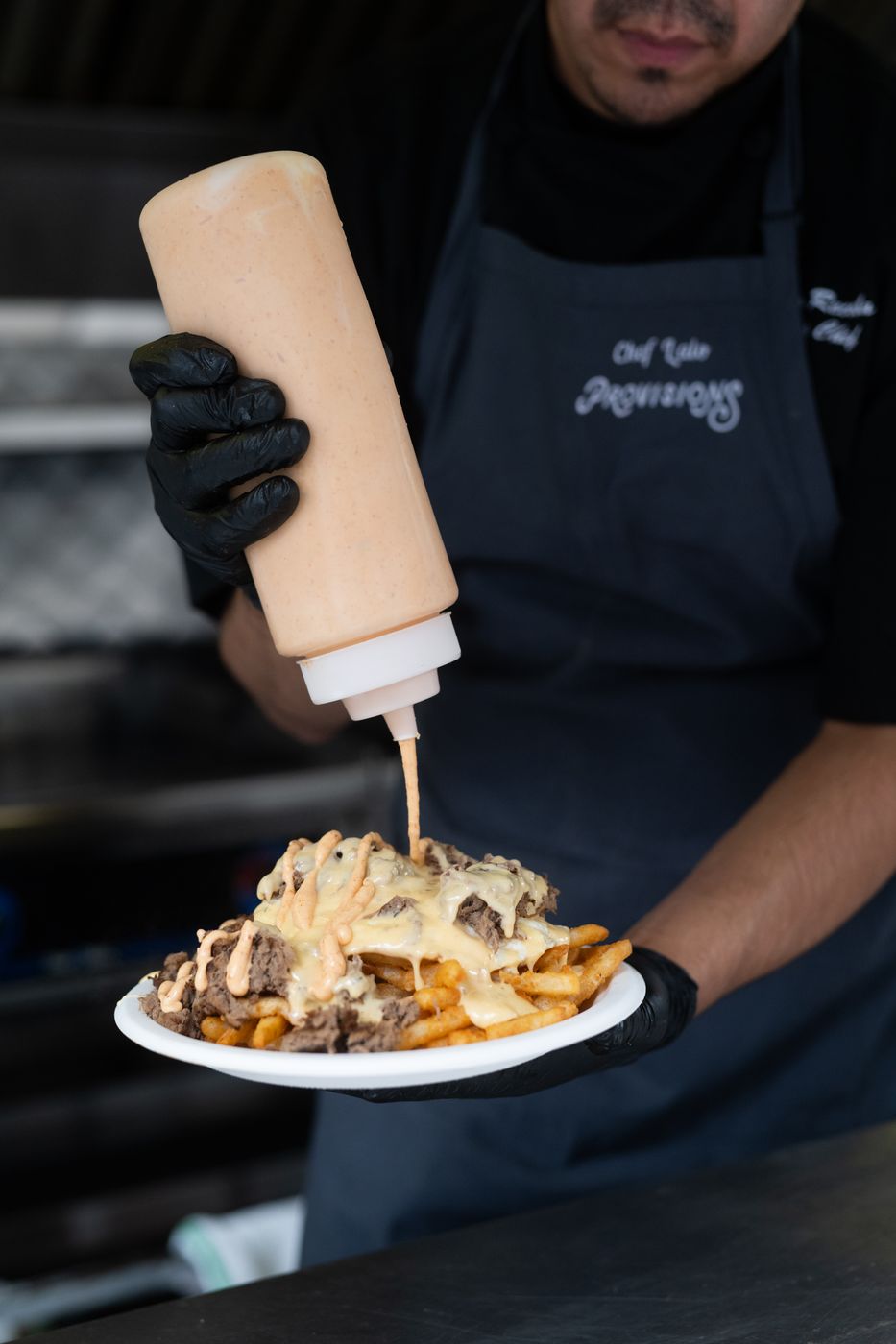 Chef adding sauce to loaded fries