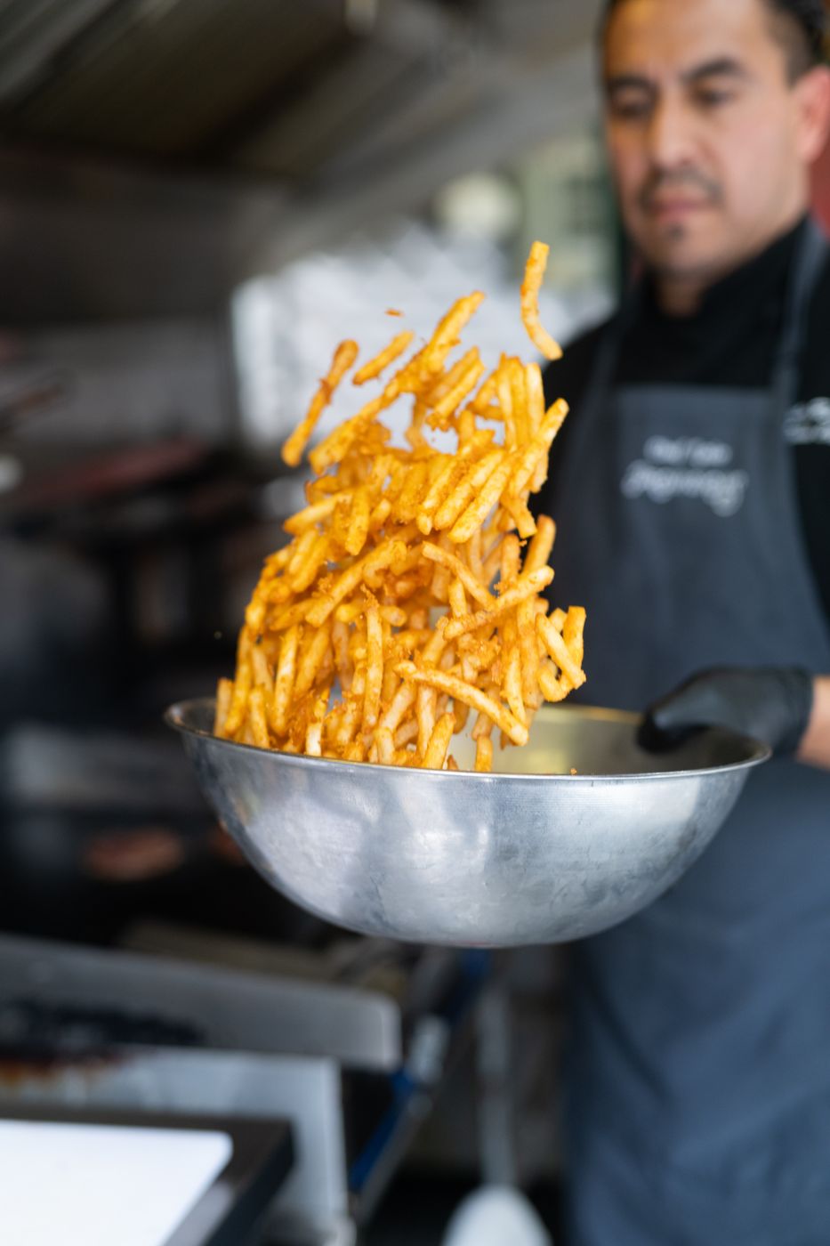 Chef tossing fries in a bowl