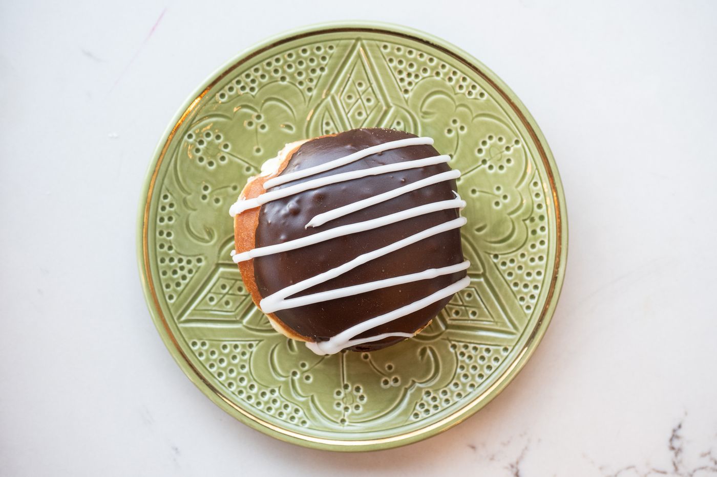 Chocolate glazed donut with a white drizzle
