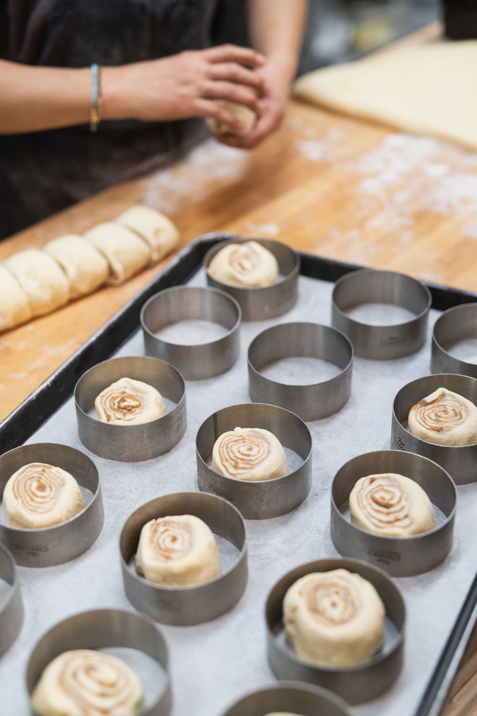 Cinnamon rolls proofing in rings on a baking tray