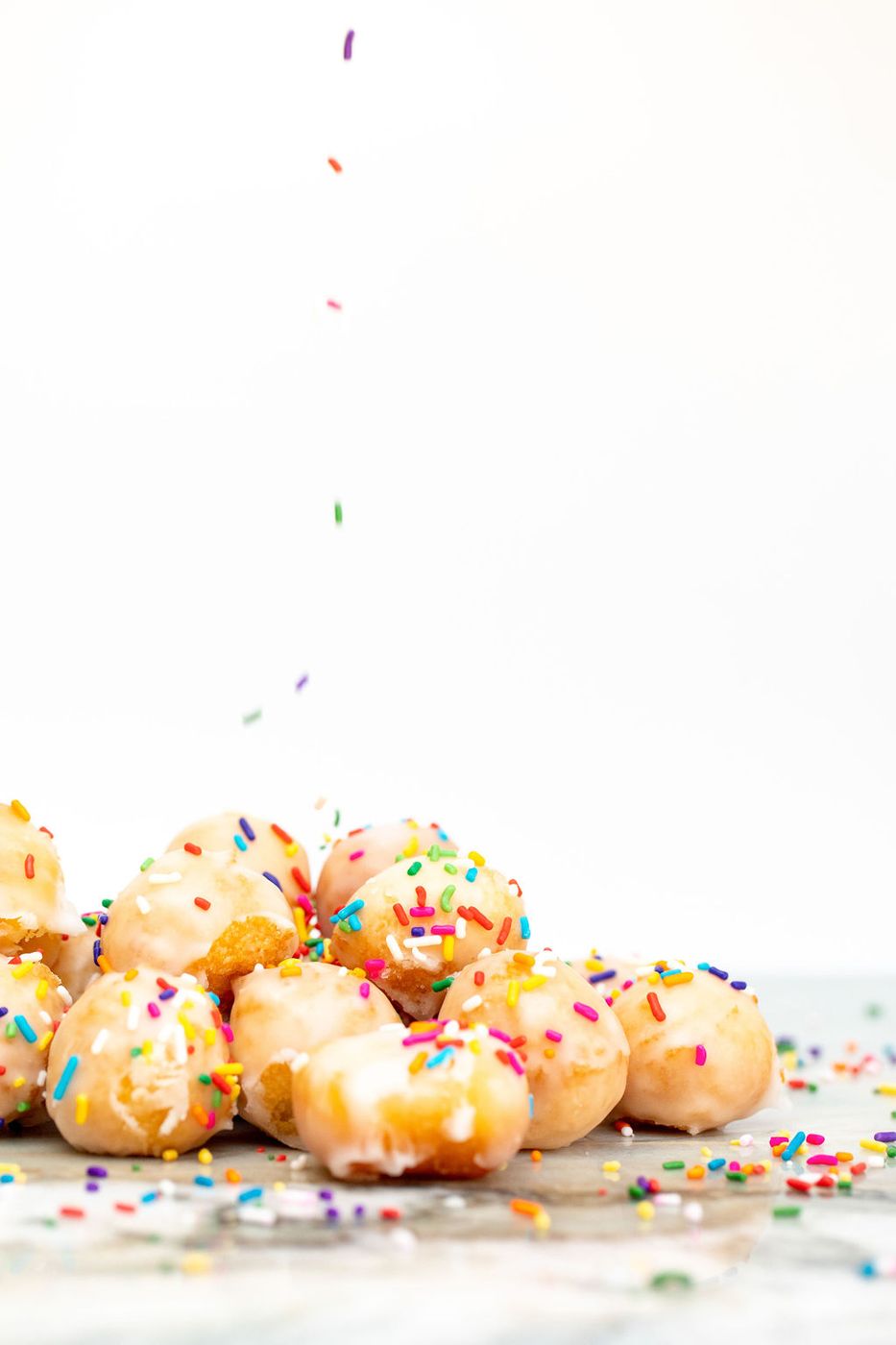 Sprinkles falling onto glazed donut holes