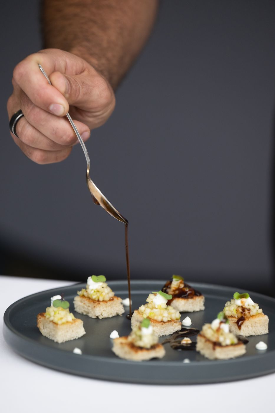 Chef drizzling sauce over canapés