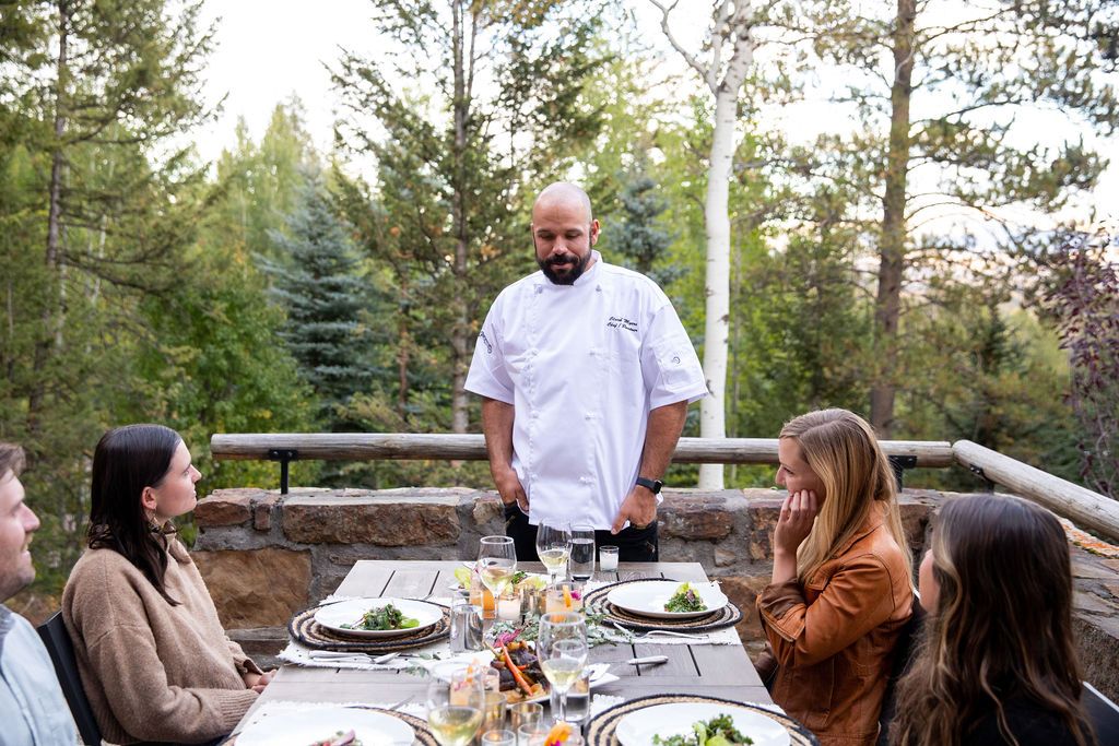 Chef talking with guests at a dinner on the deck