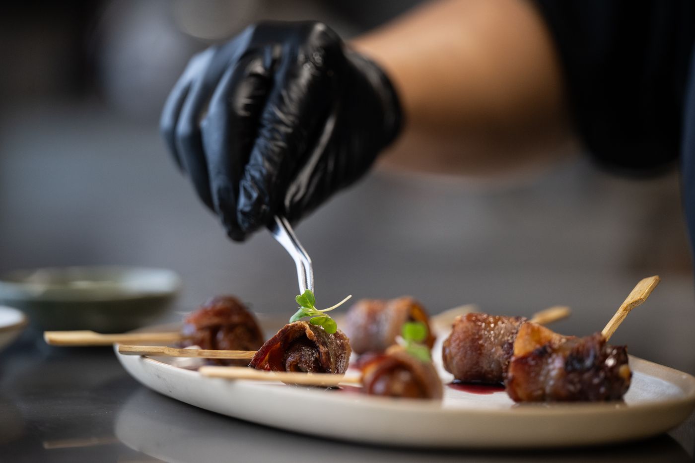 Chef plating skewers with tweezers