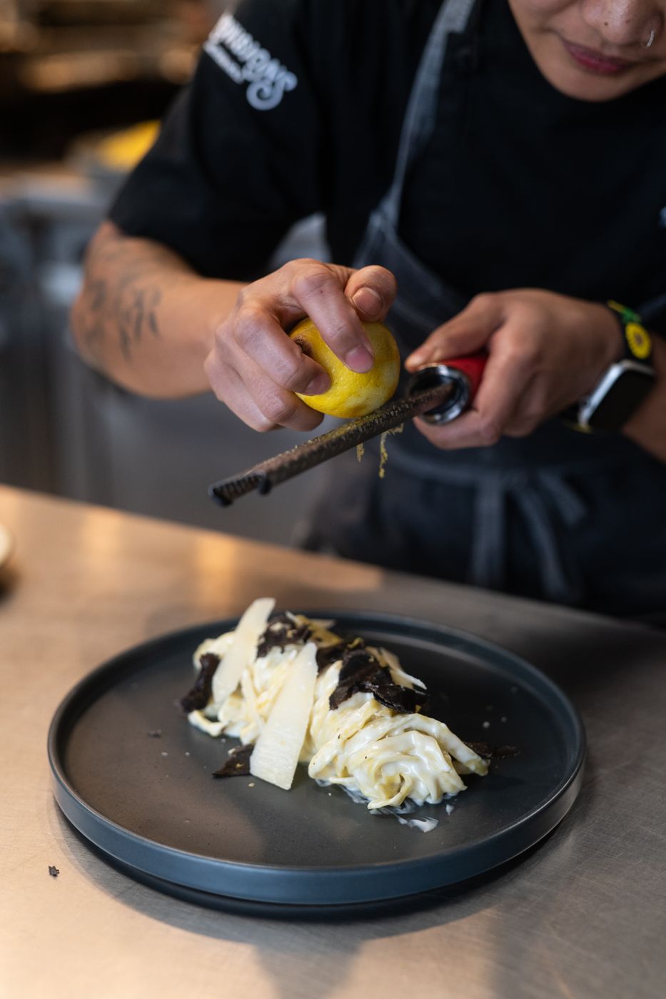 Chef zesting lemon over fresh pasta