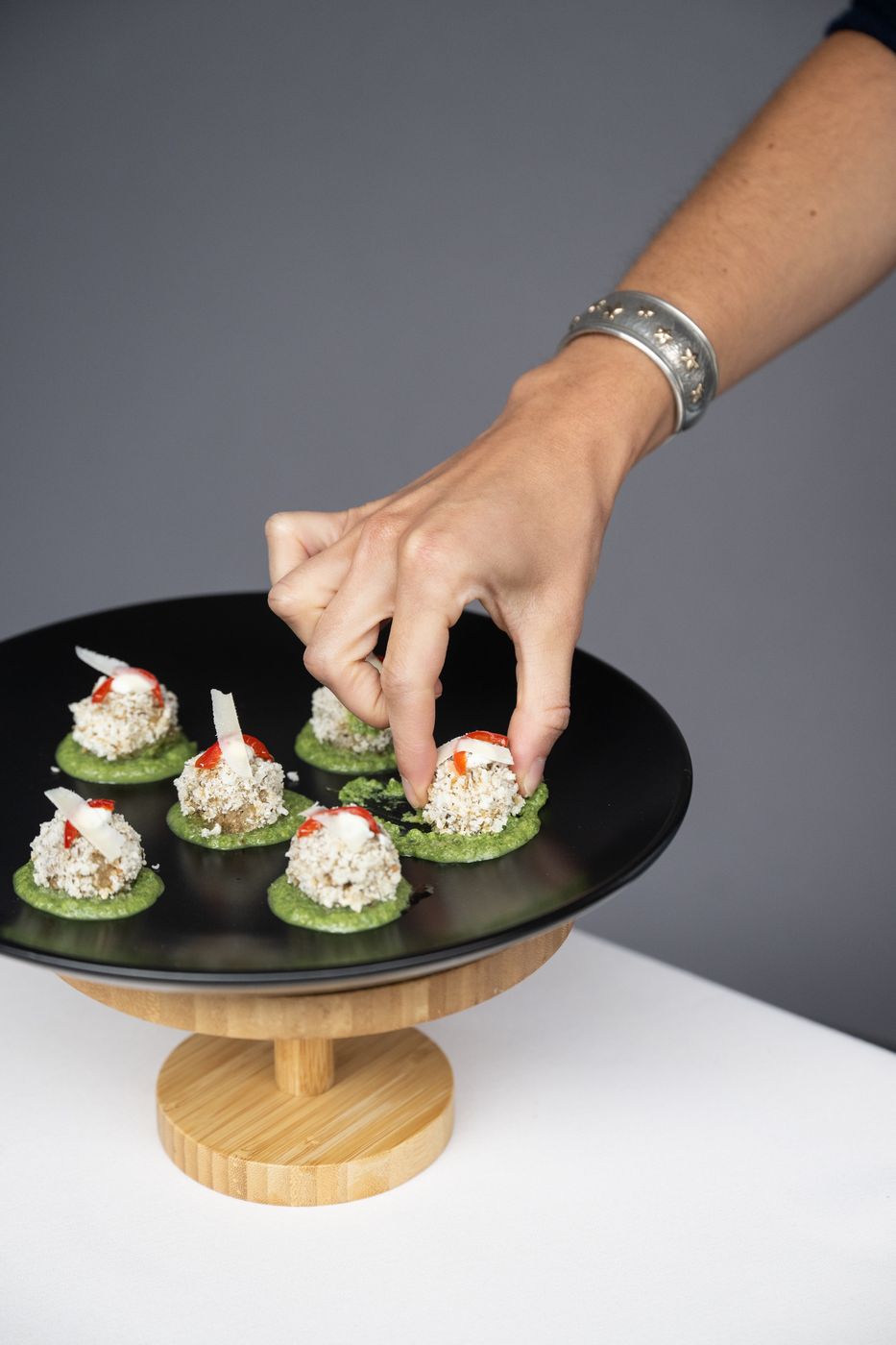 Hand placing a canapé on a cake stand