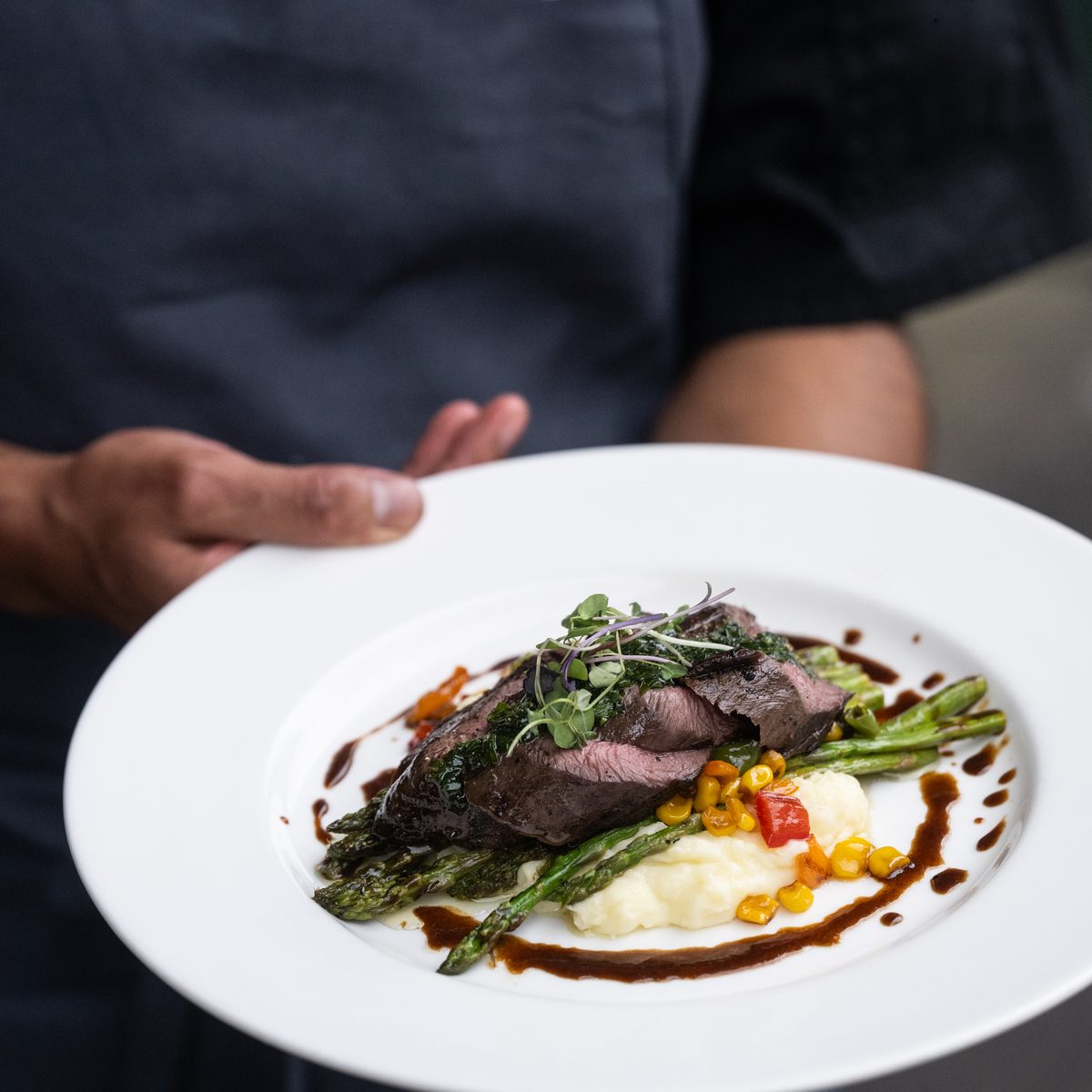 Provisions chef holding a plate of steak with whipped potatoes and asparagus for a private dinner