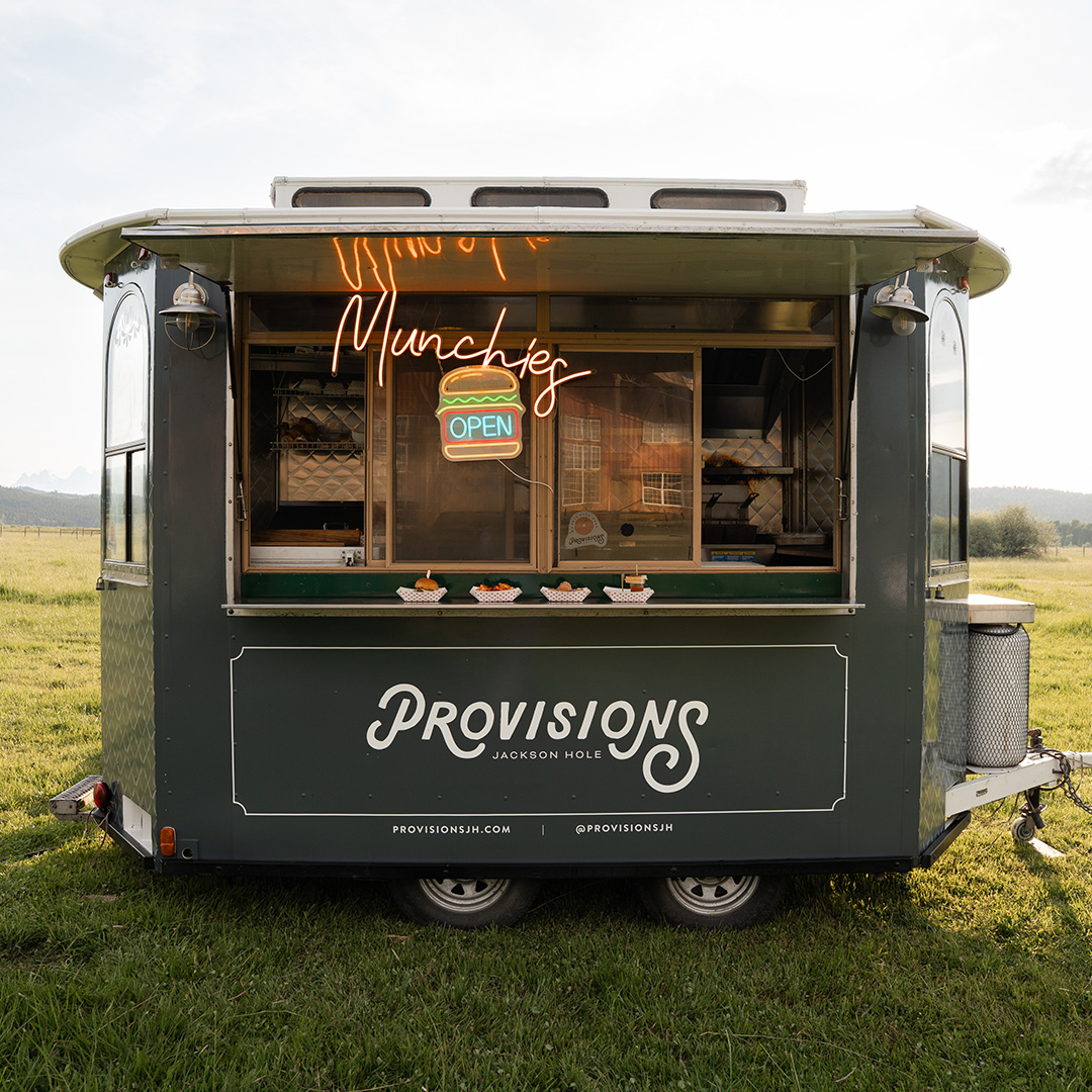The Provisions vintage trolley food truck in a meadow with the Tetons behind it