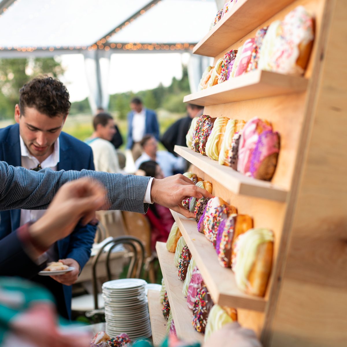 Wedding guests picking donuts from a Provisions donut wall under a tent in Jackson Hole